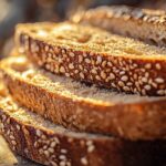 A golden, rustic loaf of einkorn bread on a wooden cutting board, surrounded by wheat stalks and a jar of honey for a wholesome, homemade feel.