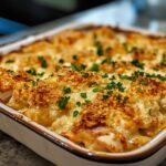 Chicken and dressing recipe served in a casserole dish with golden crust and fresh parsley garnish.