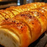 Crusty Italian bread recipe featuring a golden loaf with a soft, airy interior on a wooden cutting board, accompanied by olive oil and fresh rosemary.