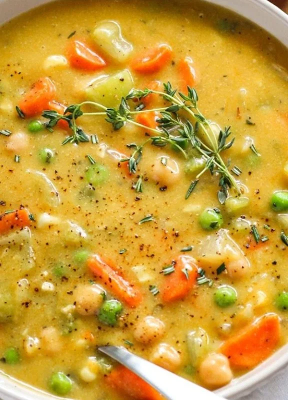 Bowl of creamy vegetable soup with fresh vegetables and herbs