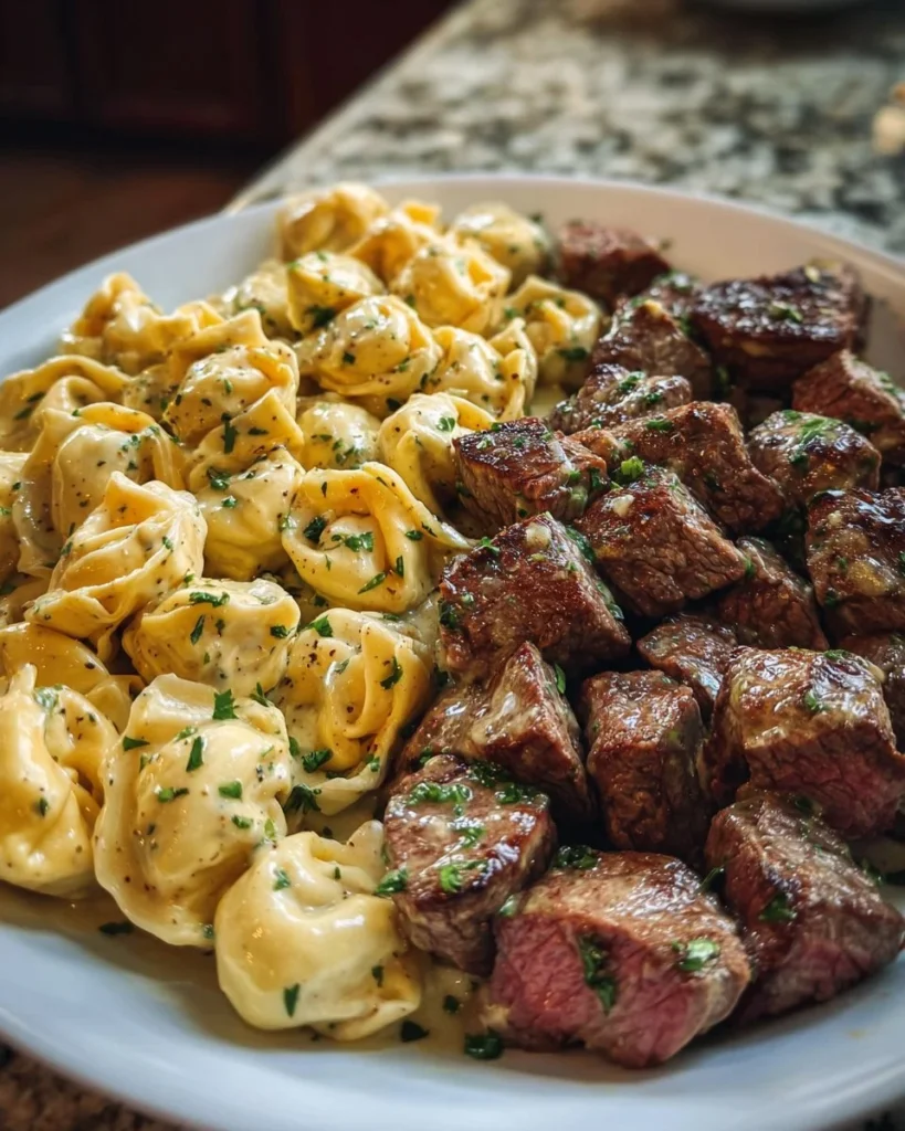 Garlic butter steak bites served with creamy alfredo tortellini on a plate