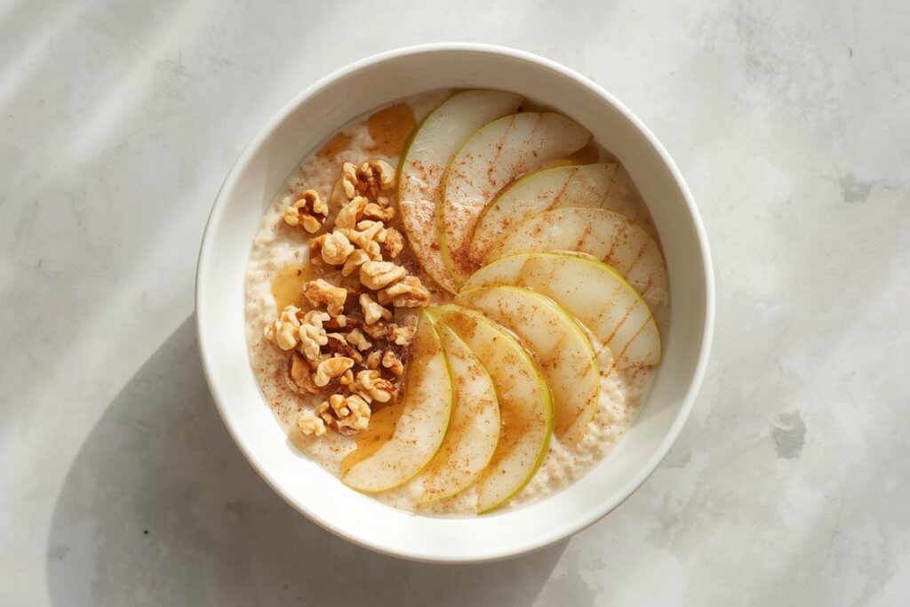 Creamy spiced pear and walnut elevated overnight oats in a white bowl, garnished with fresh pear slices and crushed walnuts.