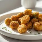 Golden-brown crispy air fryer holiday sides, specifically Brussels sprouts, artfully plated on a white ceramic dish.