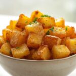 A large bowl of golden, ultra crispy air fryer potatoes, seasoned with herbs, ready to serve. Perfect for a no pre-boil recipe.