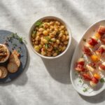 An elegant spread of no-cook holiday side dishes: cranberry-pecan goat cheese, Mediterranean white bean salad, and prosciutto skewers.