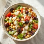 Vibrant Mediterranean chickpea salad bowl with white feta and lemon-tahini dressing, a creative chickpea meal.